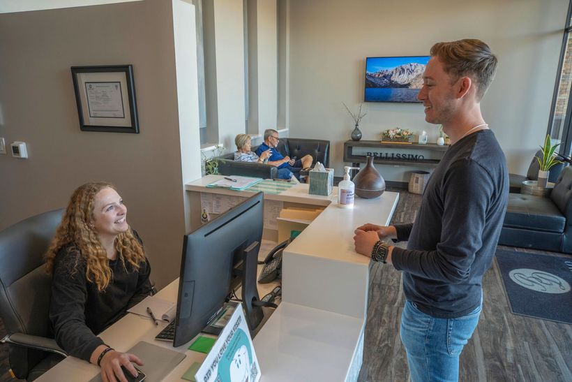 A patient at the Bellissimo Dentistry reception desk